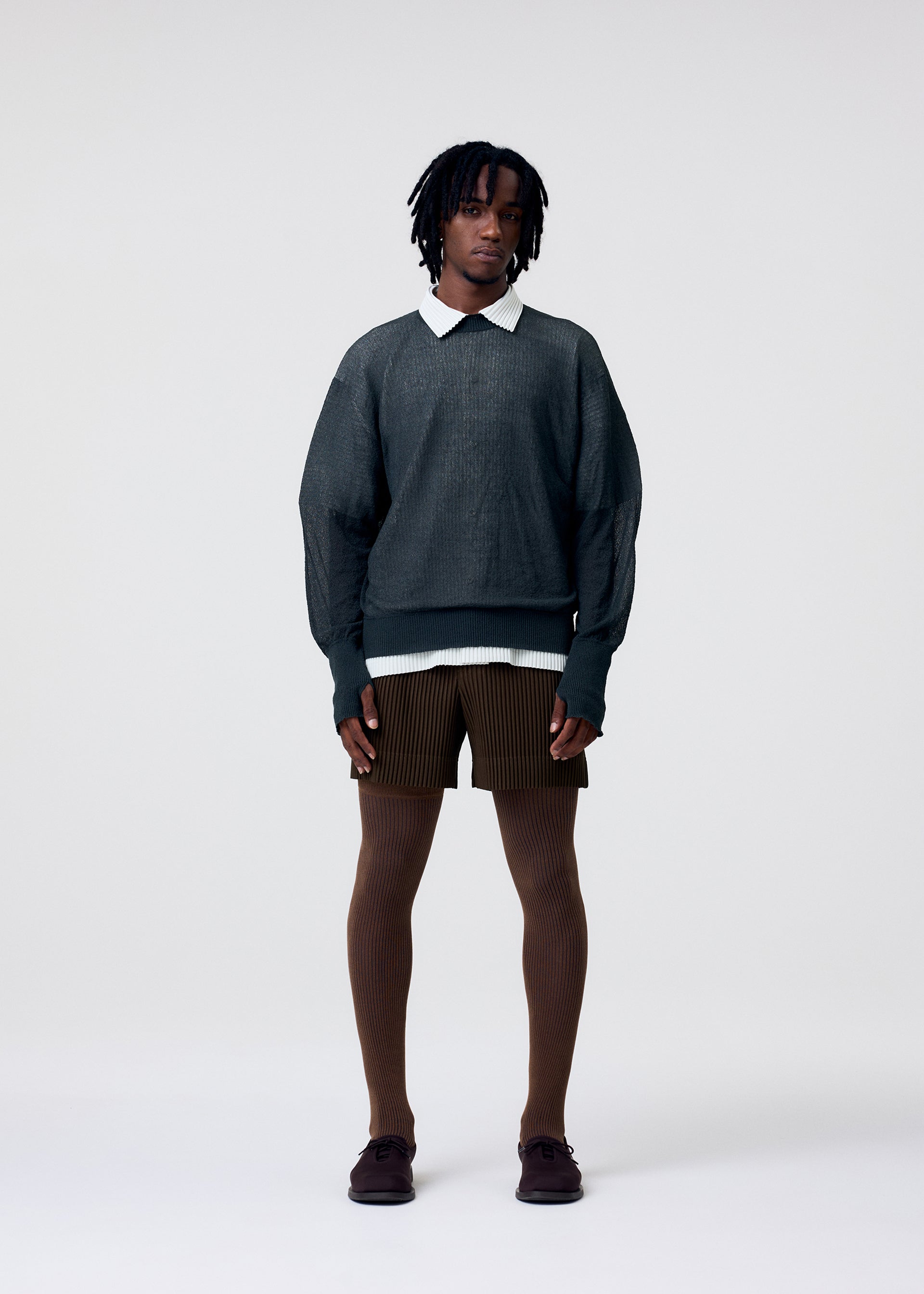 A model wears the HOMME PLISSÉ ISSEY MIYAKE TAILORED PLEATS 3 tailored-pleats-3-trousers-black.