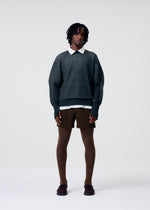 A model wears the HOMME PLISSÉ ISSEY MIYAKE TAILORED PLEATS 3 tailored-pleats-3-trousers-genova-metal-ochre-1.