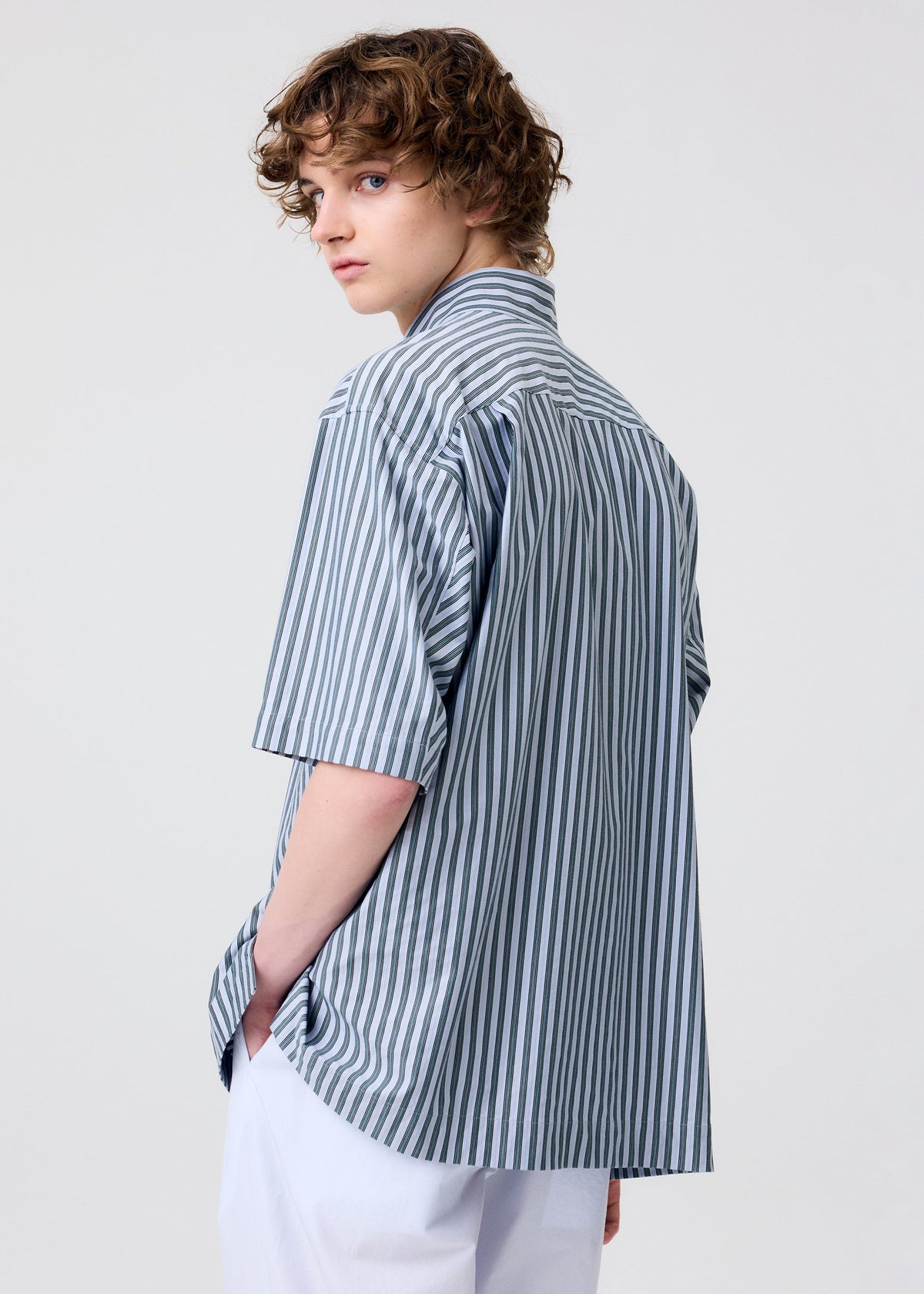 A model wears the Homme Plisse Issey Miyake STRIPE JERSEY shirt.