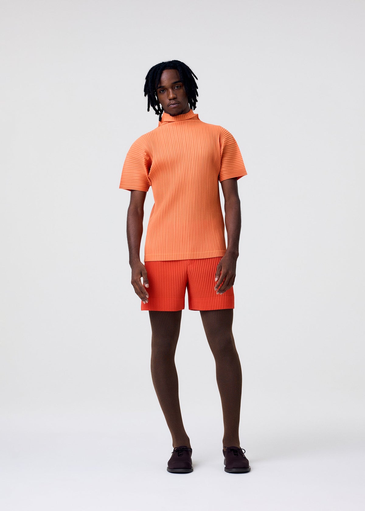 A model wears the HOMME PLISSÉ ISSEY MIYAKE AGAVE MESH agave-mesh-t-shirt-orange-1.