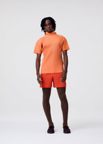 A model wears the HOMME PLISSÉ ISSEY MIYAKE AGAVE MESH agave-mesh-t-shirt-orange-1.