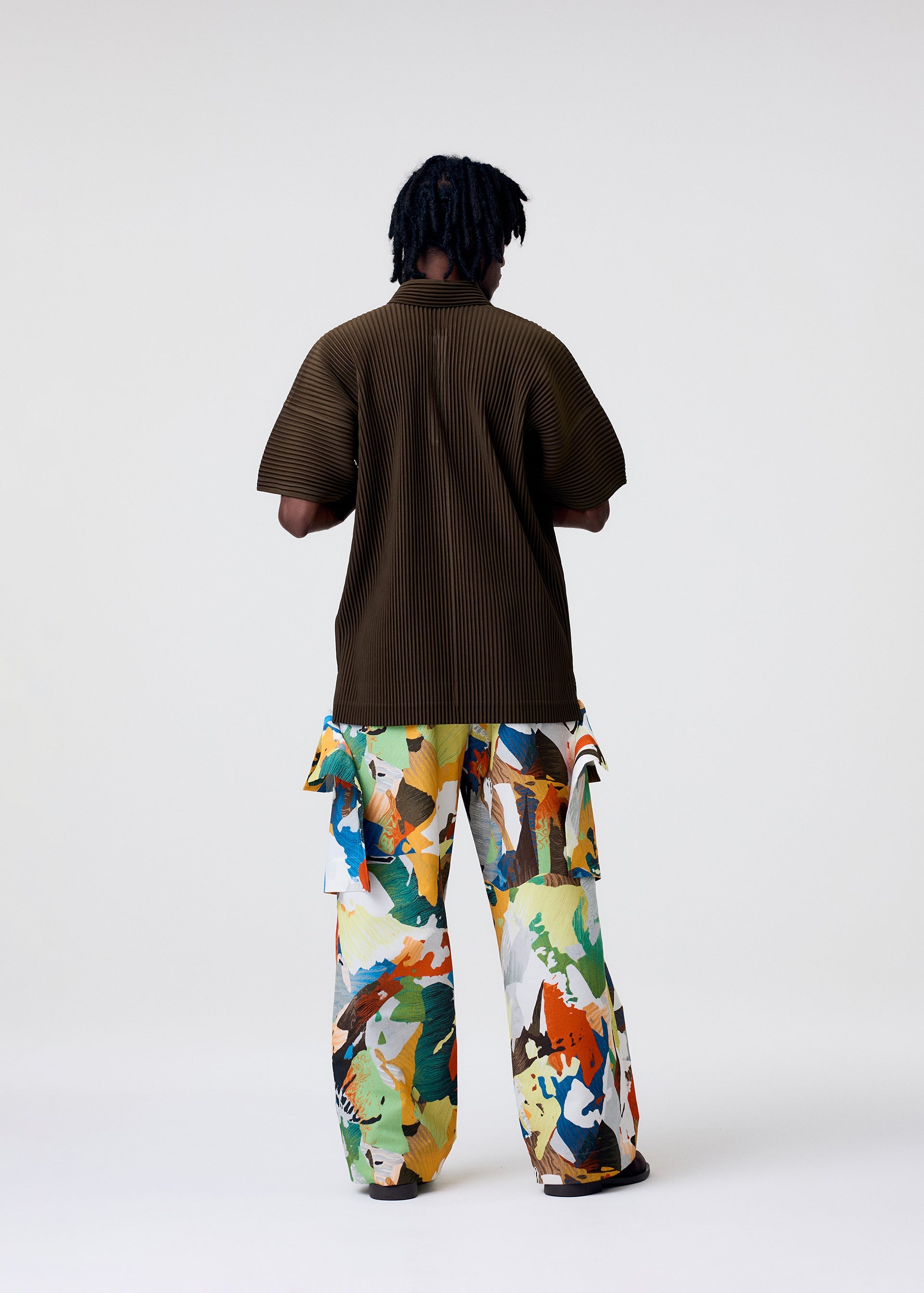 A model wears the HOMME PLISSÉ ISSEY MIYAKE MONTHLY COLORS : JUNE monthly-colors-june-polo-shirt-genova-metal-ochre.