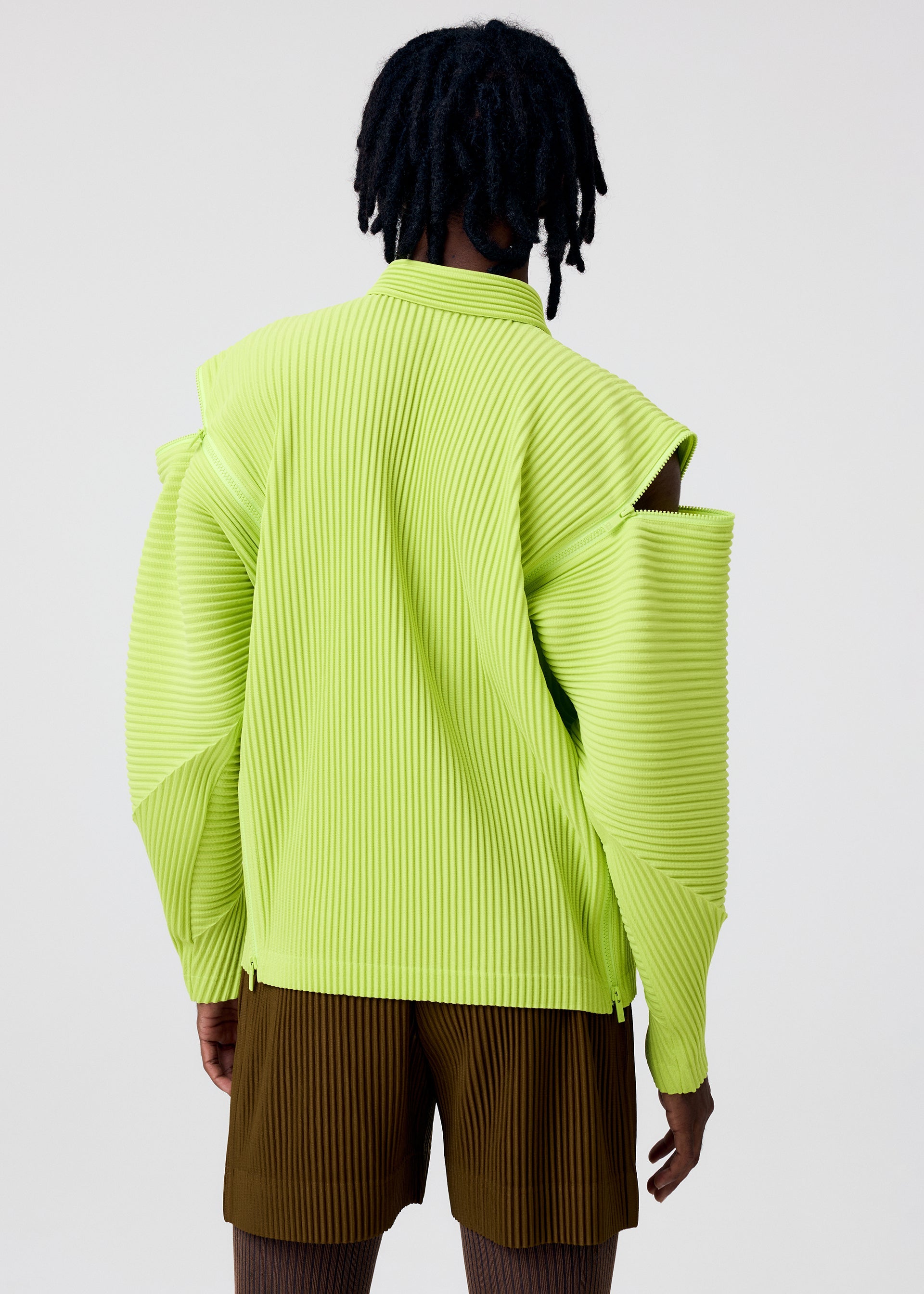 A model wears the HOMME PLISSÉ ISSEY MIYAKE MULTI-FASTENED multi-fastened-polo-shirt-pizza-scorch-brown.