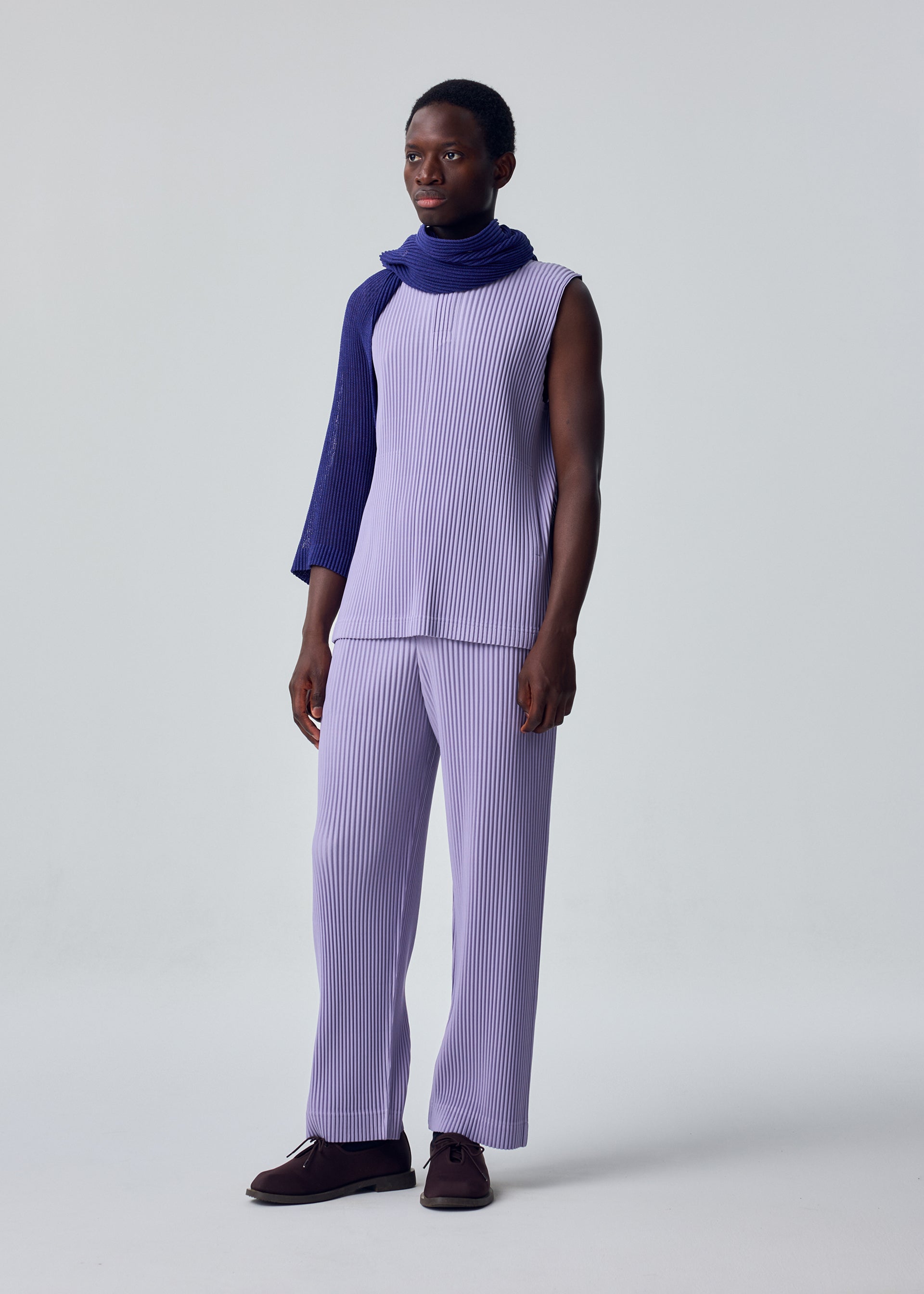 A model wears the HOMME PLISSÉ ISSEY MIYAKE RUSTIC MESH STOLE rustic-mesh-stole-stole-blue-2.