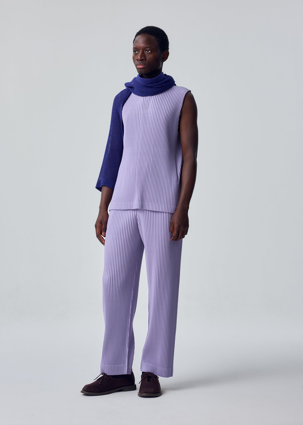 A model wears the HOMME PLISSÉ ISSEY MIYAKE RUSTIC MESH STOLE rustic-mesh-stole-stole-black.