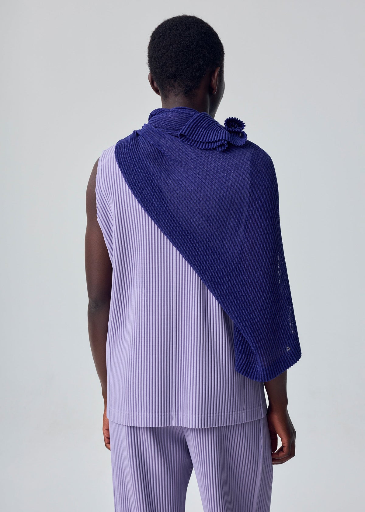 A model wears the HOMME PLISSÉ ISSEY MIYAKE RUSTIC MESH STOLE rustic-mesh-stole-stole-black.
