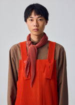 A model wears the HOMME PLISSÉ ISSEY MIYAKE PLEATS STOLE pleats-stole-stole-vermillion.