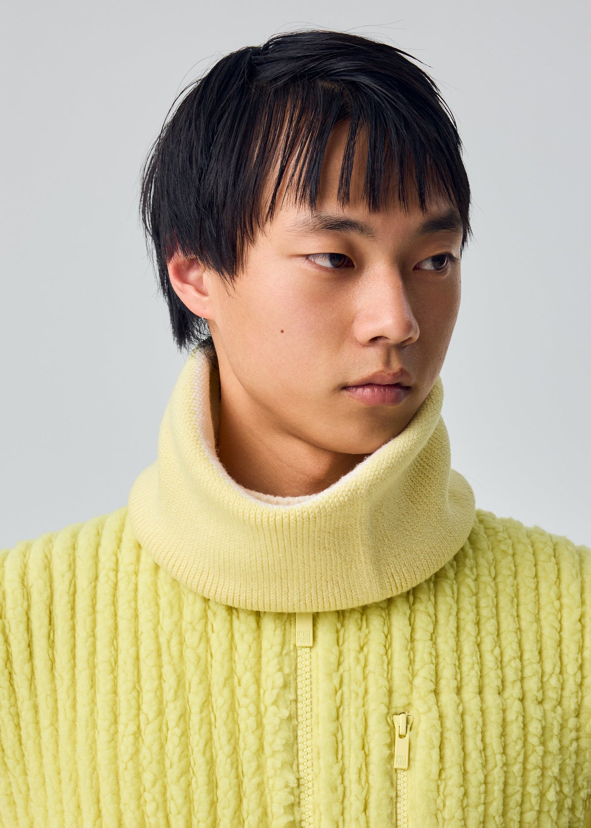A model wears the HOMME PLISSÉ ISSEY MIYAKE WINTER GEAR : COLOR BLOCK winter-gear-color-block-neckwarmer-beige.