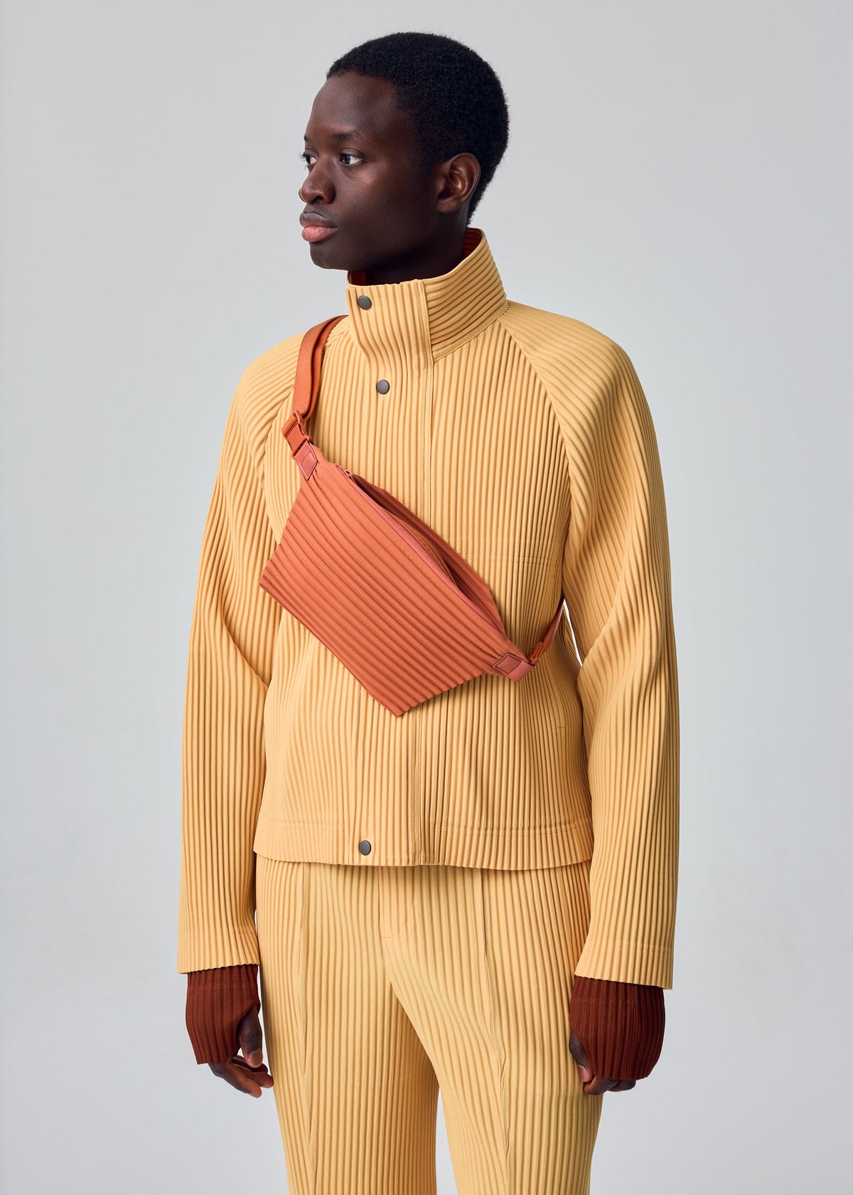 A model wears the HOMME PLISSÉ ISSEY MIYAKE PLEATS SLIM BAG pleats-slim-bag-bag-black.