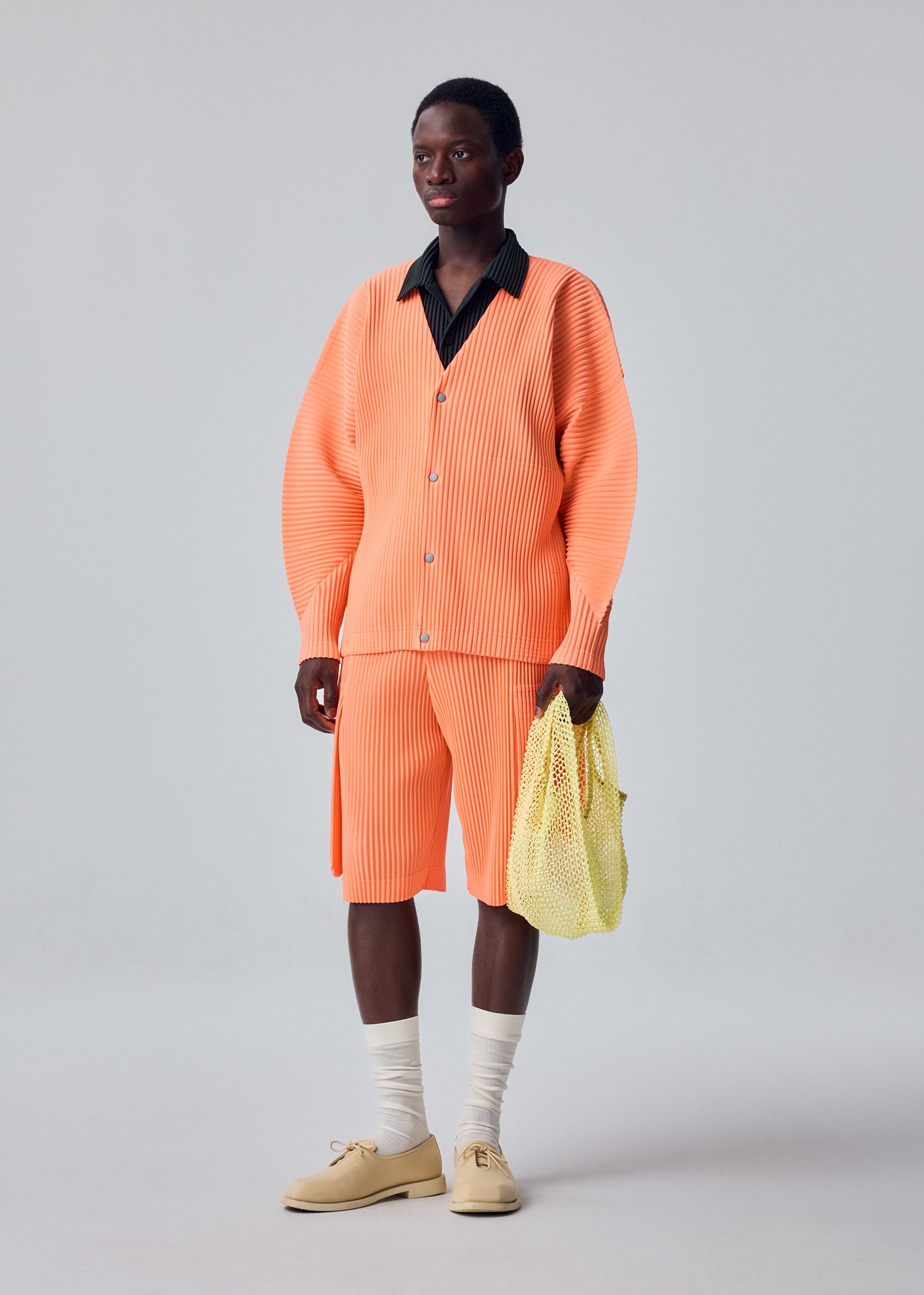 A model wears the HOMME PLISSÉ ISSEY MIYAKE MESH PLEATS BAG mesh-pleats-bag-bag-black.