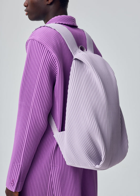 A model wears the HOMME PLISSÉ ISSEY MIYAKE PLEATS BACKPACK bag.
