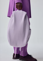 A model wears the HOMME PLISSÉ ISSEY MIYAKE PLEATS BACKPACK bag.