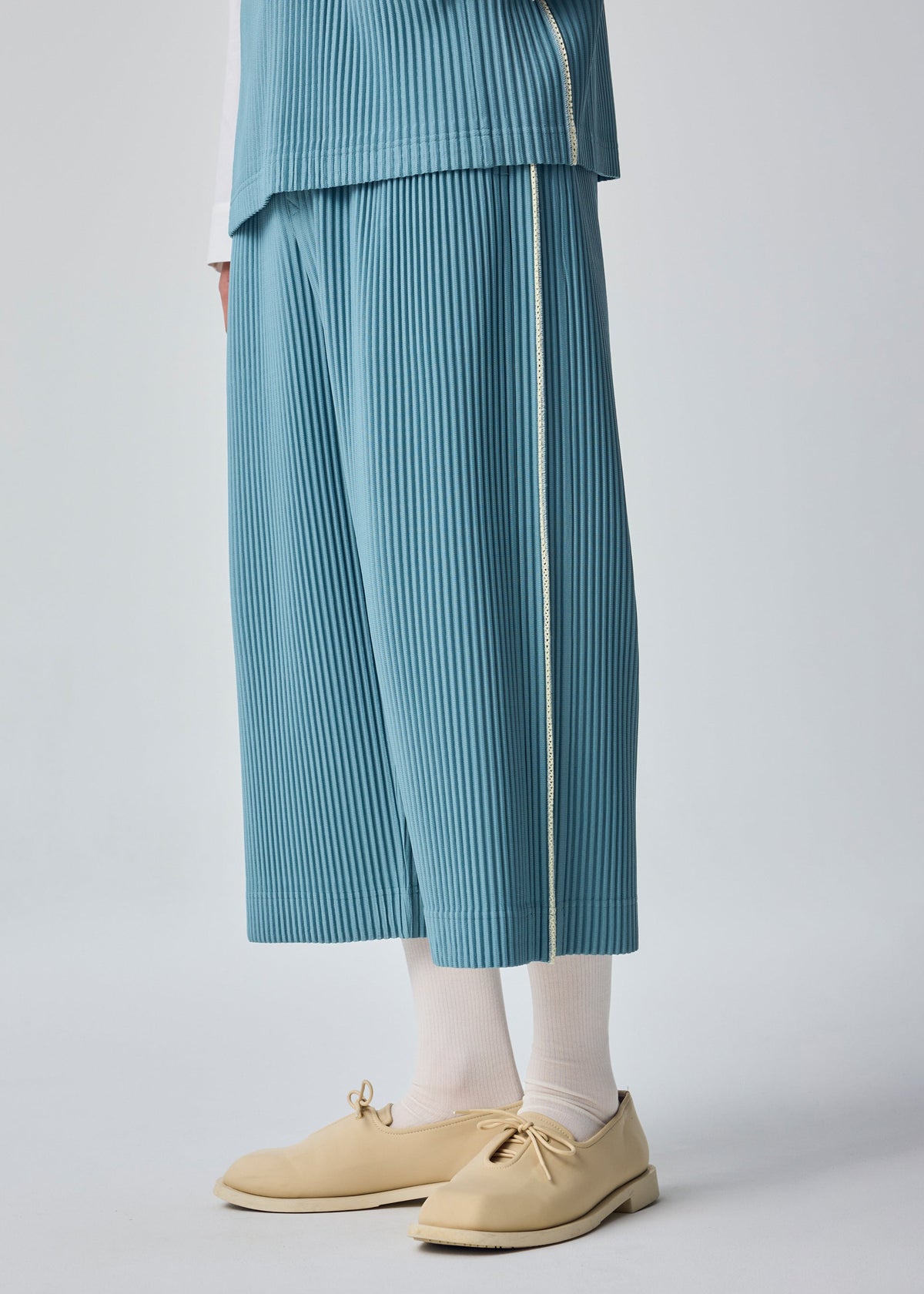 A model wears the HOMME PLISSÉ ISSEY MIYAKE SIMPLE SOCKS simple-socks-socks-white.