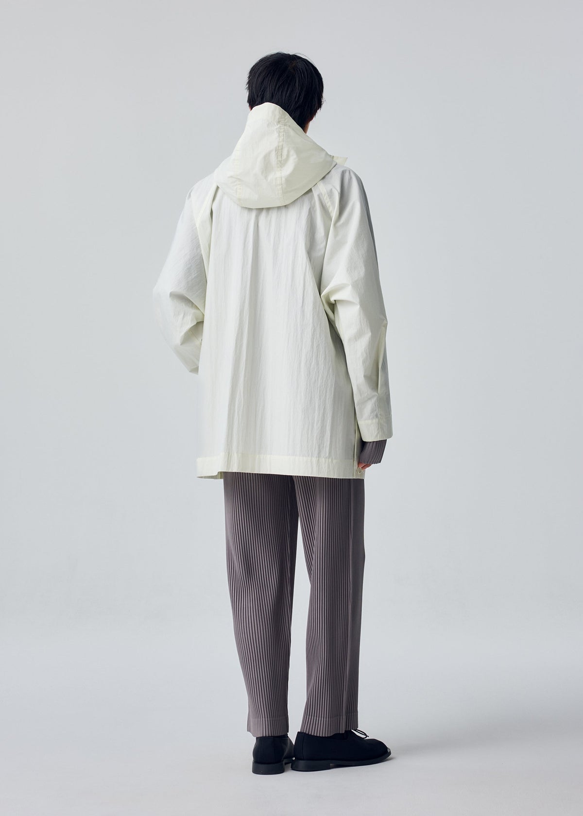 A model wears the HOMME PLISSÉ ISSEY MIYAKE SLIT COAT blouson.