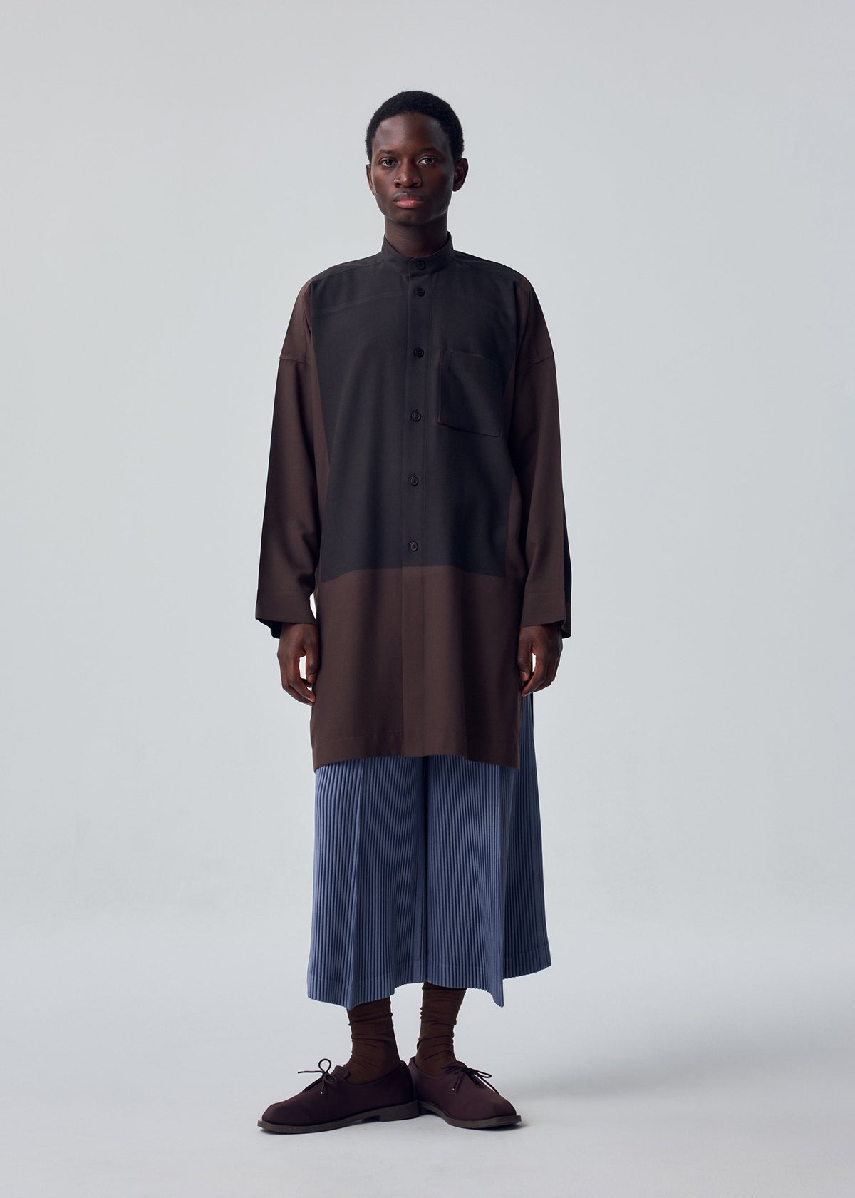 A model wears the HOMME PLISSÉ ISSEY MIYAKE KERSEY PLEATS trousers.