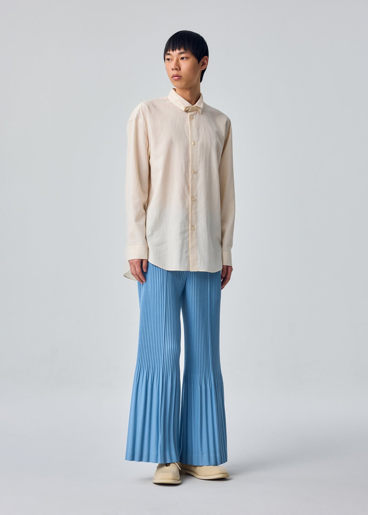 A model wears the HOMME PLISSÉ ISSEY MIYAKE PL RAMIE SHIRT pl-ramie-shirt-shirt-beige-1.