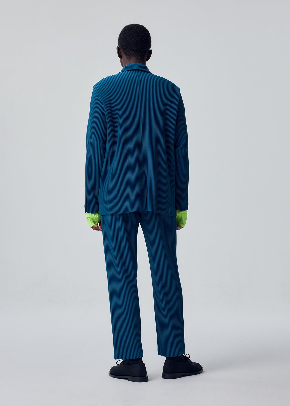 A model wears the HOMME PLISSÉ ISSEY MIYAKE TAILORED PLEATS 1 tailored-pleats-1-jacket-black-16.