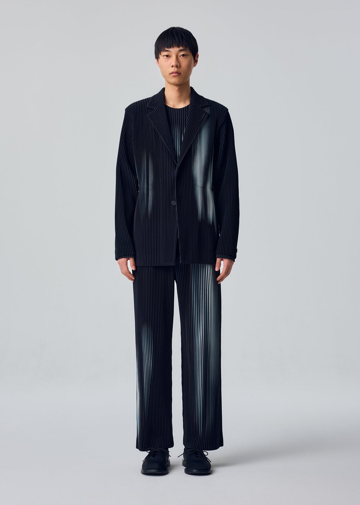 A model wears the HOMME PLISSÉ ISSEY MIYAKE IN THE SHADOW jacket.