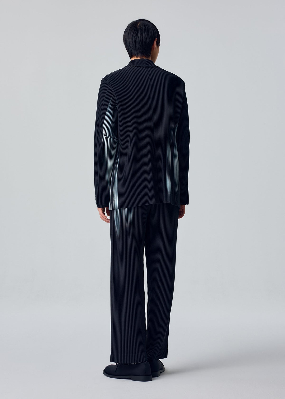 A model wears the HOMME PLISSÉ ISSEY MIYAKE IN THE SHADOW jacket.