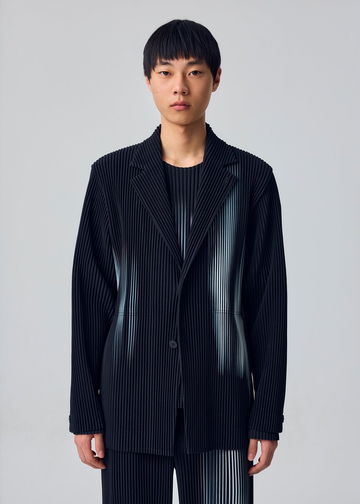 A model wears the HOMME PLISSÉ ISSEY MIYAKE IN THE SHADOW jacket.