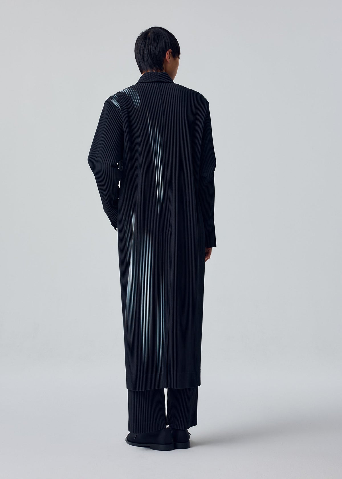 A model wears the HOMME PLISSÉ ISSEY MIYAKE IN THE SHADOW jacket.