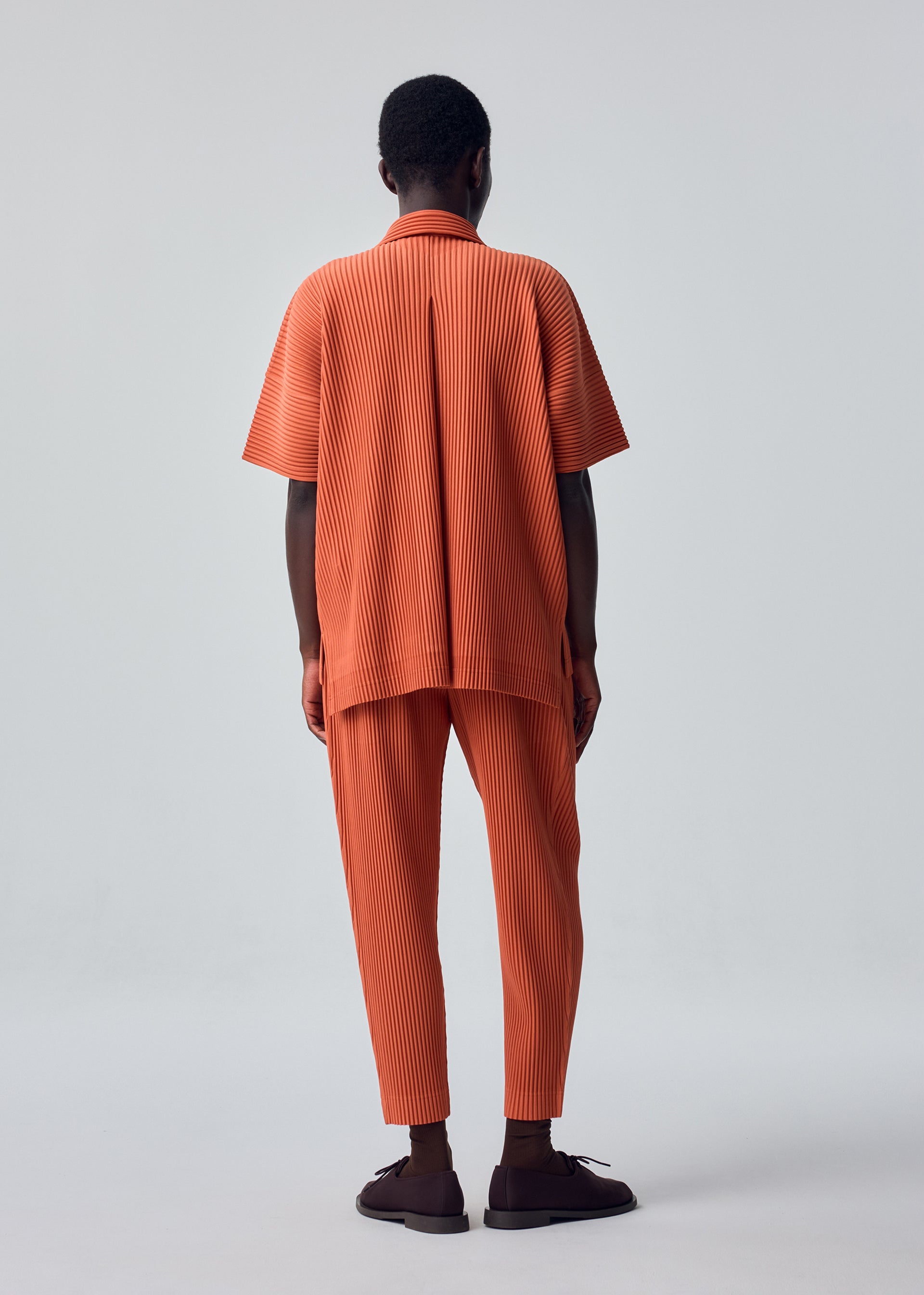 A model wears the HOMME PLISSÉ ISSEY MIYAKE MONTHLY COLORS : AUGUST monthly-colors-august-trousers-black-4.