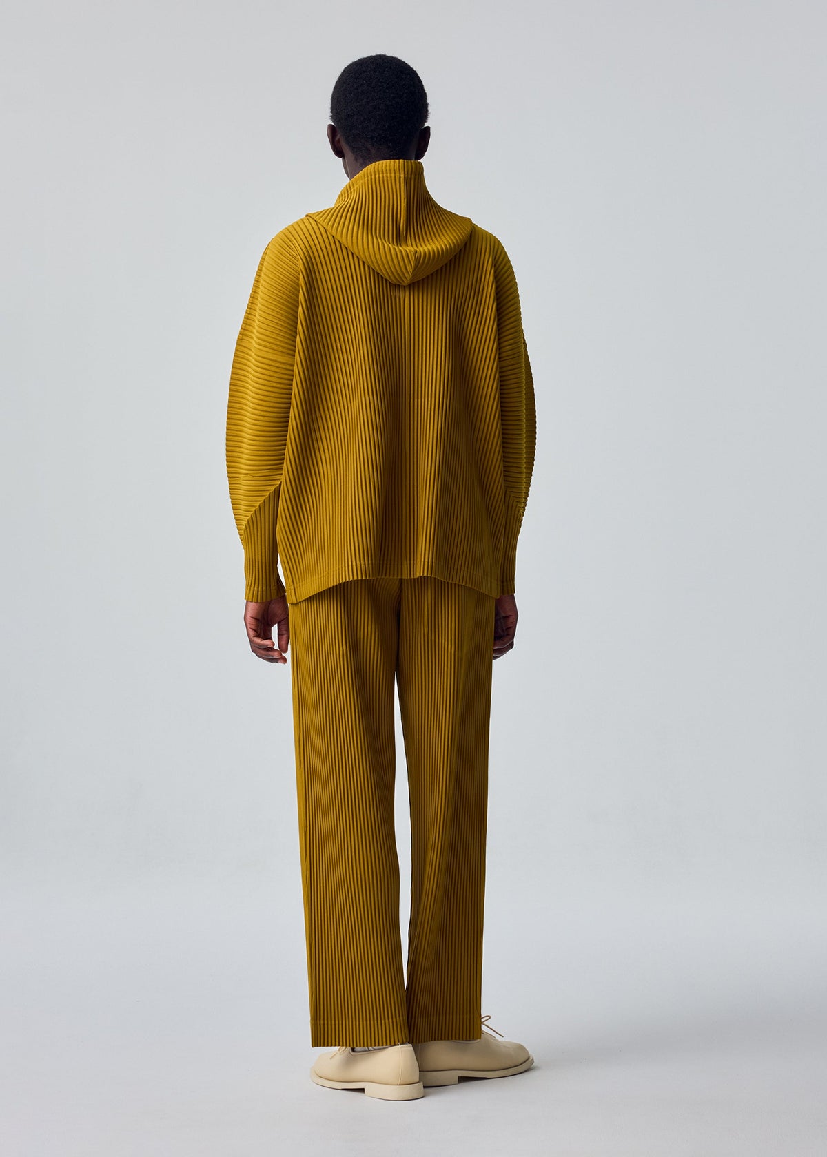 A model wears the HOMME PLISSÉ ISSEY MIYAKE MONTHLY COLORS : OCTOBER trousers.