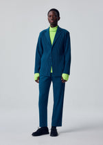 A model wears the HOMME PLISSÉ ISSEY MIYAKE TAILORED PLEATS 1 tailored-pleats-1-trousers-glow-orange.