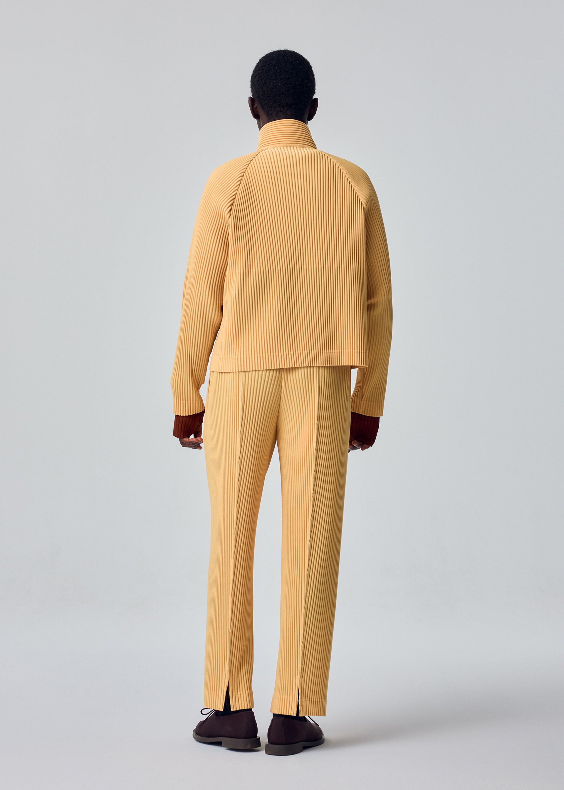 A model wears the HOMME PLISSÉ ISSEY MIYAKE TAILORED PLEATS 1 tailored-pleats-1-trousers-black-10.