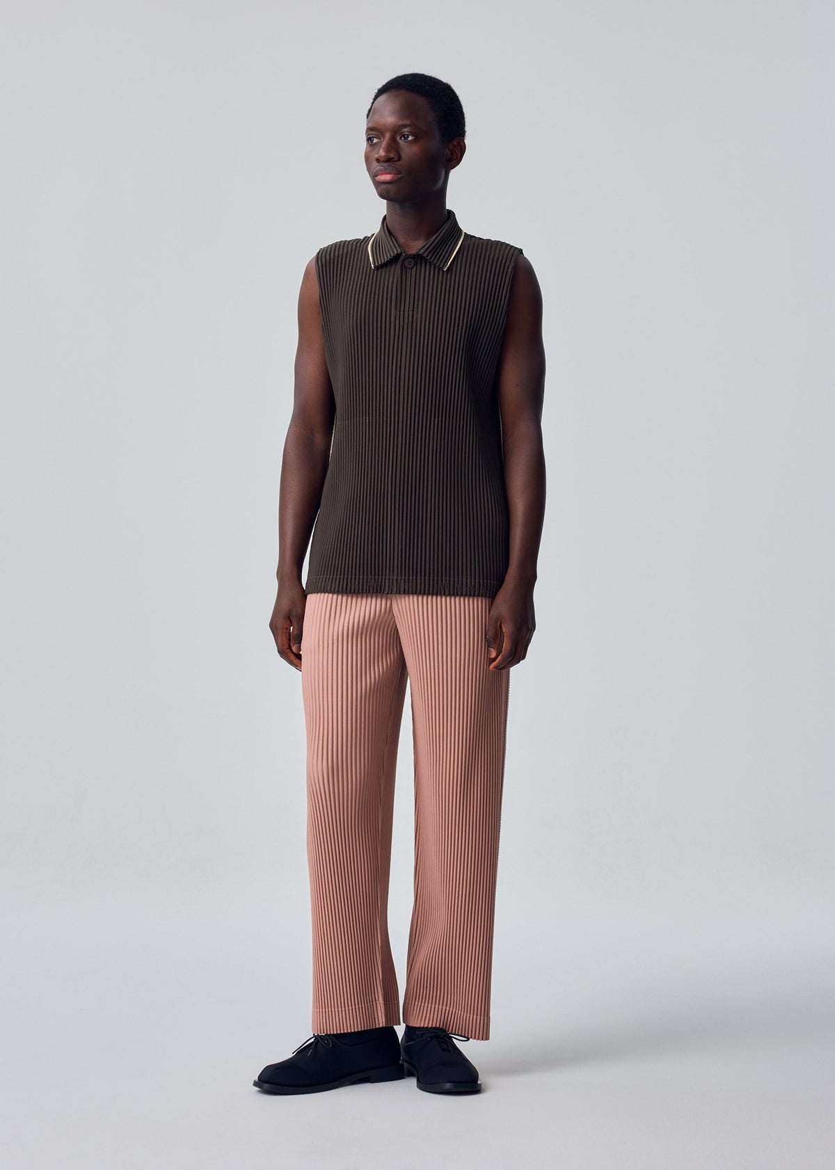A model wears the HOMME PLISSÉ ISSEY MIYAKE EMBROIDERY STRIPES embroidery-stripes-trousers-gloom-blue.