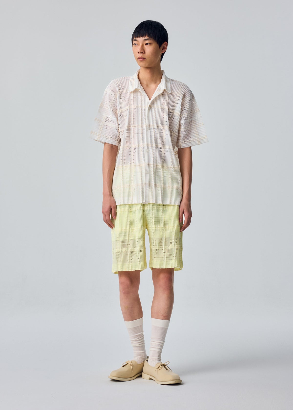 A model wears the HOMME PLISSÉ ISSEY MIYAKE LACE GRID PLEATS lace-grid-pleats-shorts-black.