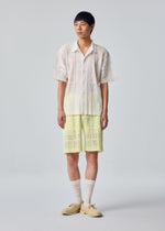 A model wears the HOMME PLISSÉ ISSEY MIYAKE LACE GRID PLEATS lace-grid-pleats-shorts-white.