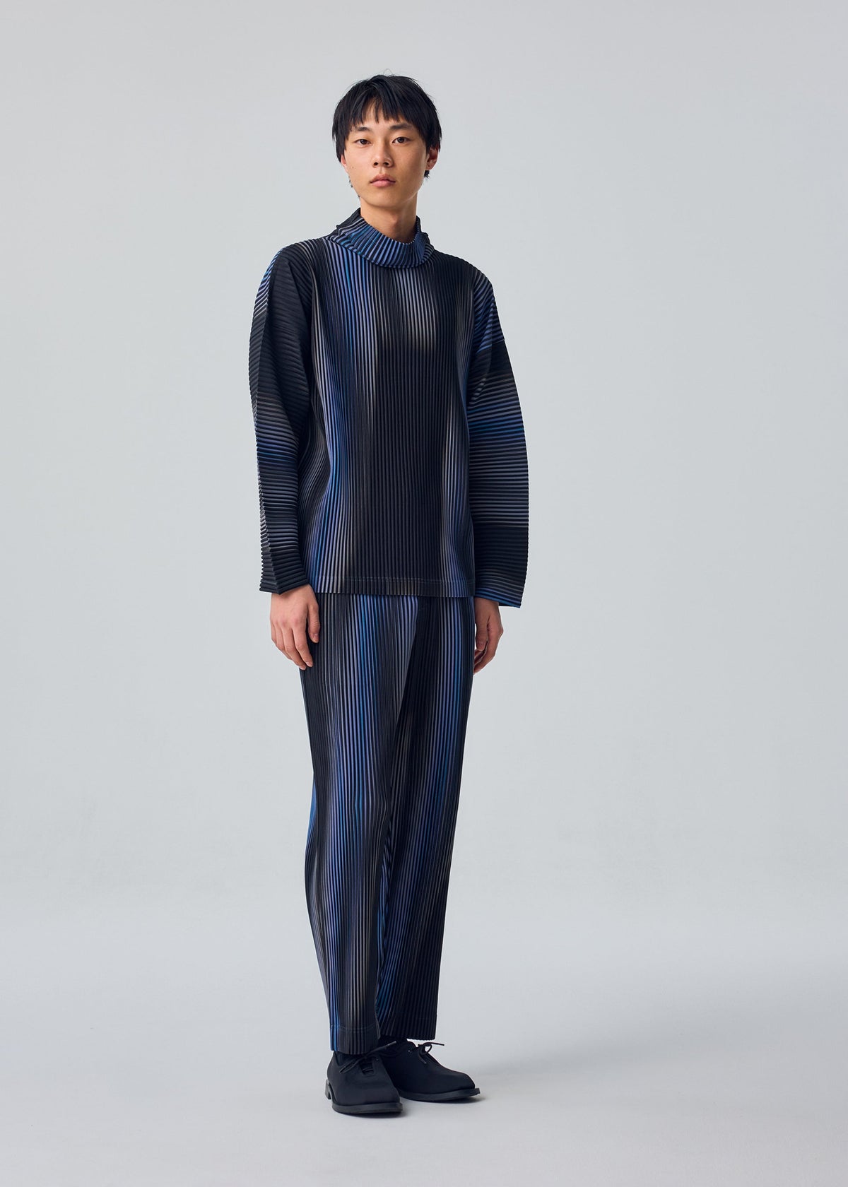 A model wears the HOMME PLISSÉ ISSEY MIYAKE BLEND OF LIGHTS blend-of-lights-trousers-brown.