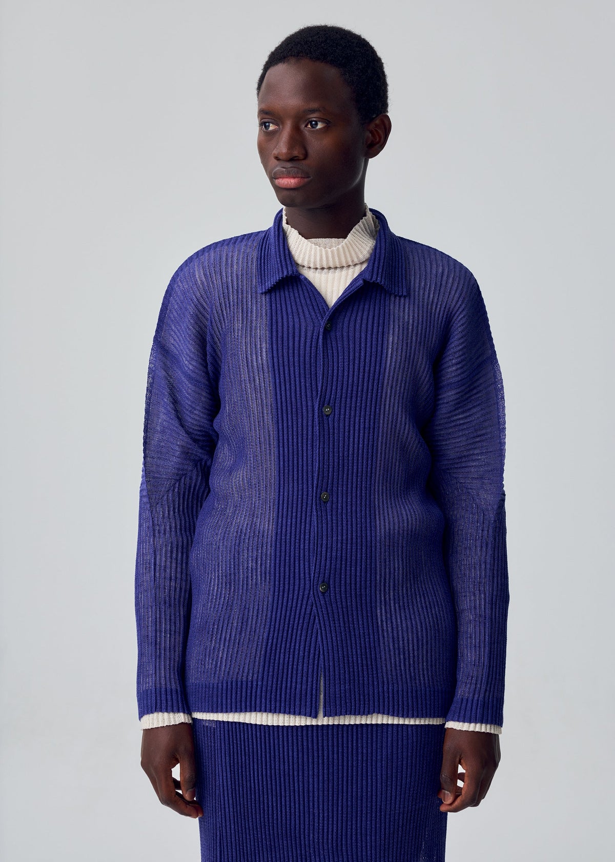 A model wears the HOMME PLISSÉ ISSEY MIYAKE RUSTIC MESH rustic-mesh-shirt-black.