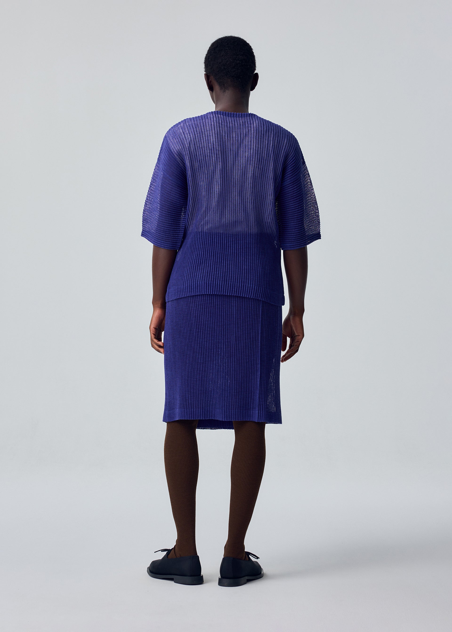 A model wears the HOMME PLISSÉ ISSEY MIYAKE RUSTIC MESH rustic-mesh-t-shirt-black.