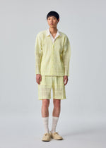 A model wears the HOMME PLISSÉ ISSEY MIYAKE LACE GRID PLEATS lace-grid-pleats-blouson-white.