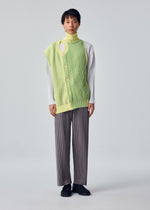 A model wears the HOMME PLISSÉ ISSEY MIYAKE IN THE SHADOW KNIT cardigan.