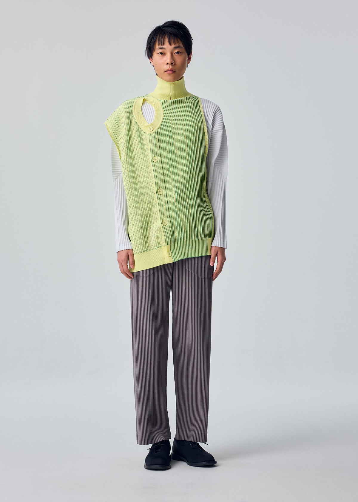 A model wears the HOMME PLISSÉ ISSEY MIYAKE IN THE SHADOW KNIT cardigan.