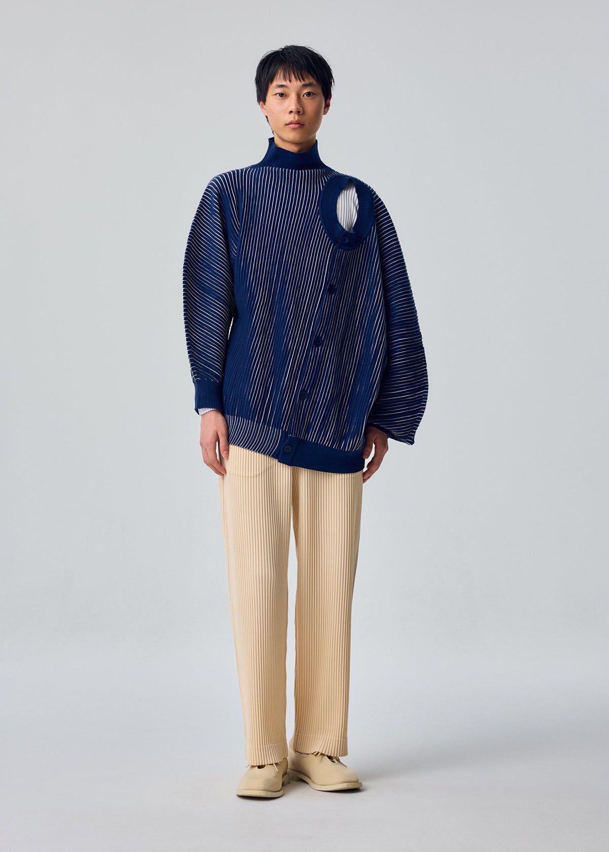 A model wears the HOMME PLISSÉ ISSEY MIYAKE IN THE SHADOW KNIT knit.