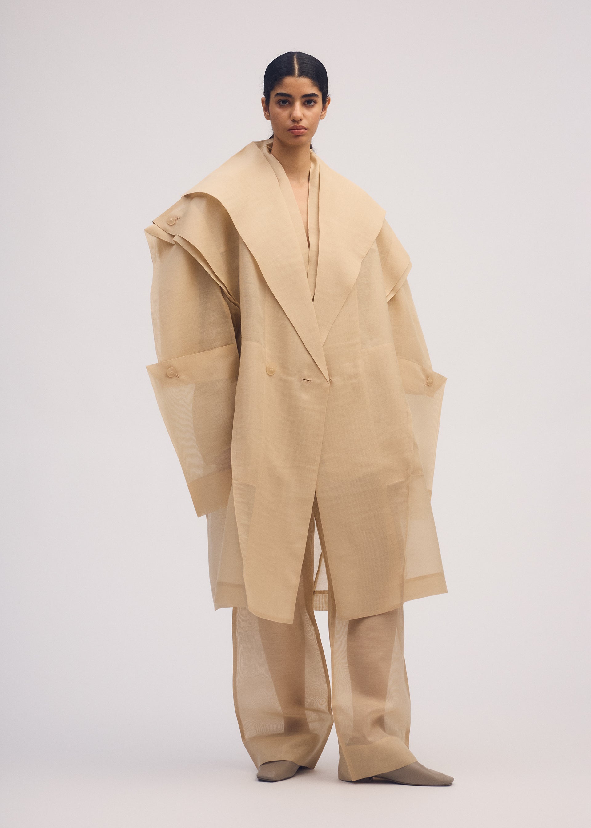 A model wears the ISSEY MIYAKE PRESS AND PRESSED coat.