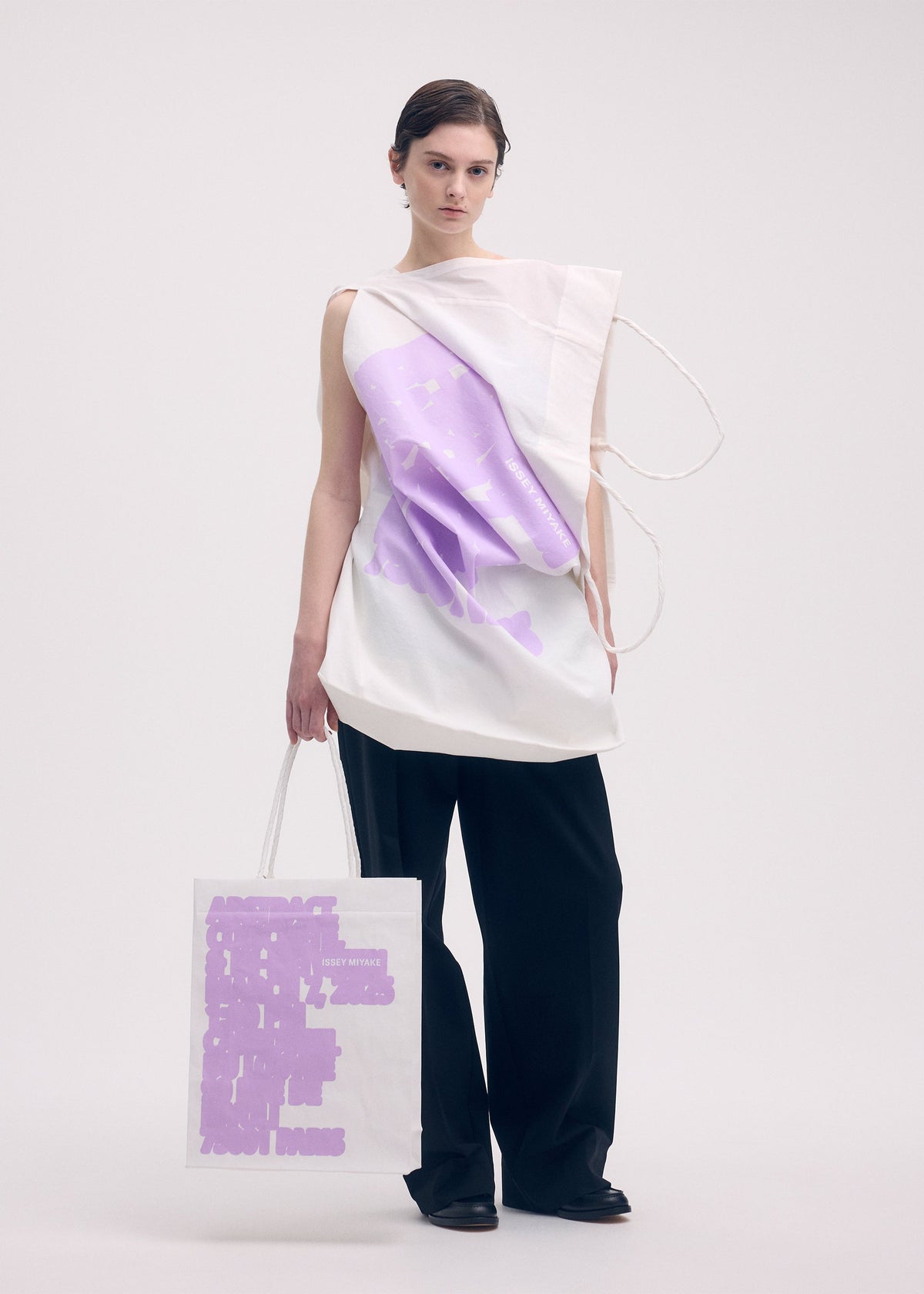 A model wears the ISSEY MIYAKE THIS IS A PAPER BAG (POSTER) bag.