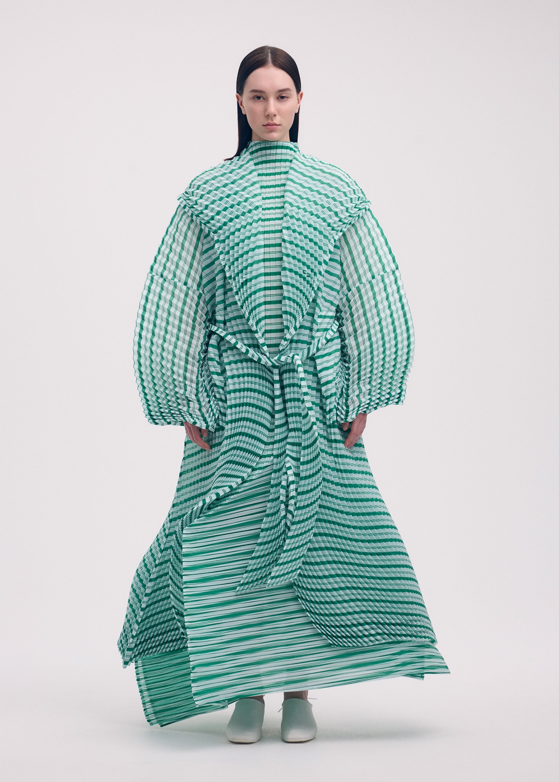 A model wears the Issey Miyake GENERIC STRIPES HAND PLEATS coat.