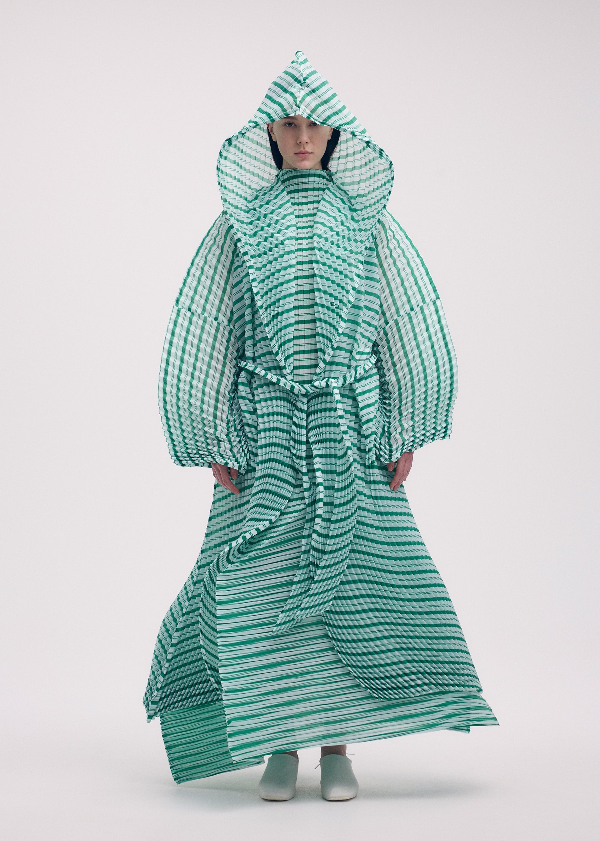 A model wears the Issey Miyake GENERIC STRIPES HAND PLEATS coat.