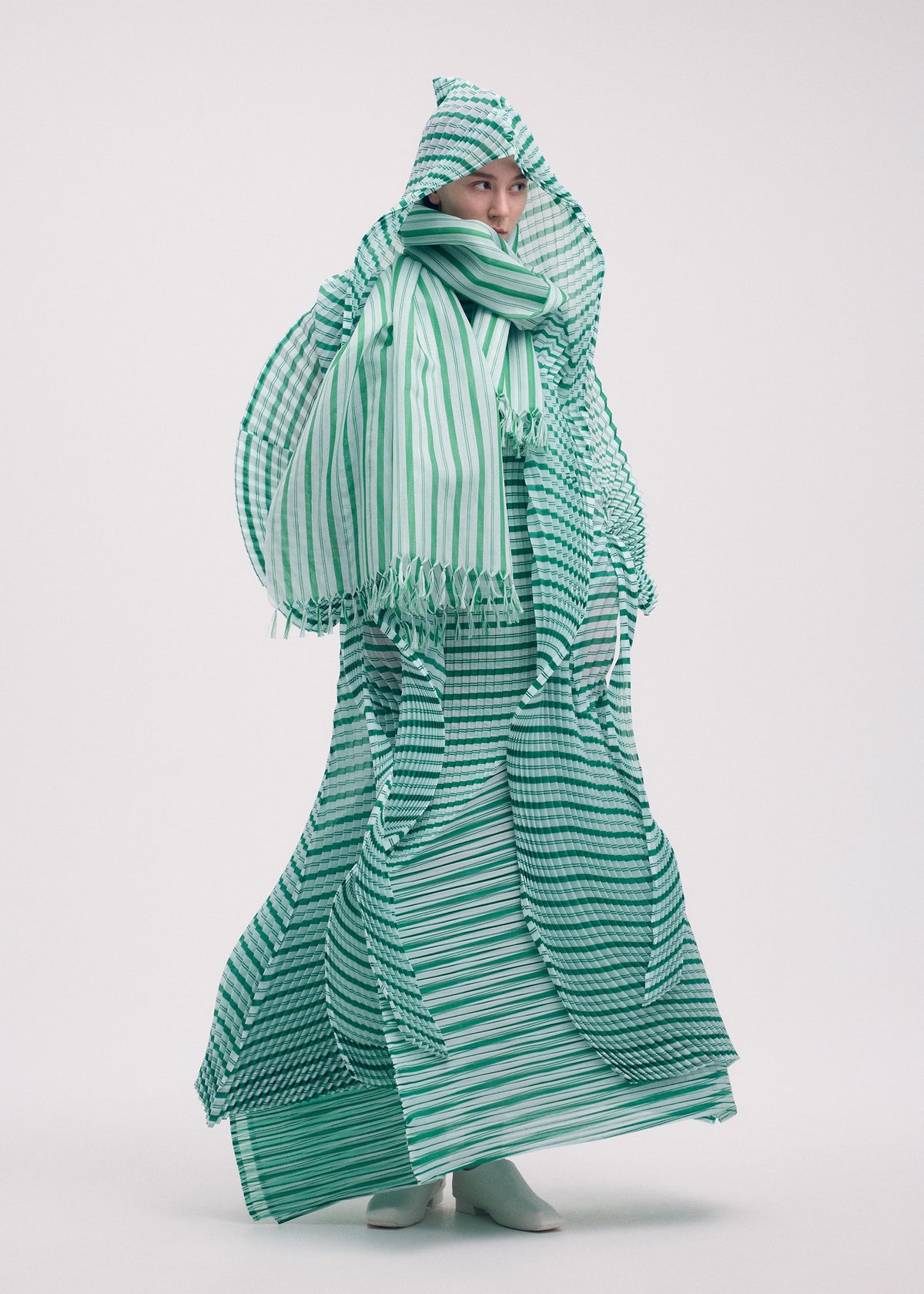 A model wears the Issey Miyake GENERIC STRIPES HAND PLEATS coat.