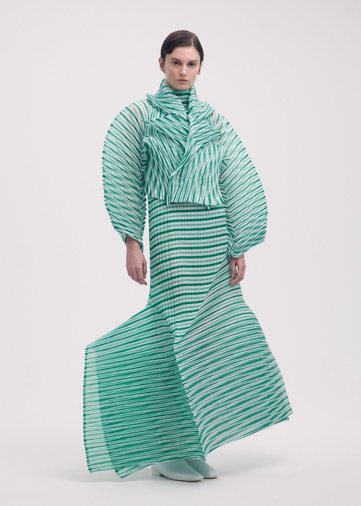 A model wears the Issey Miyake GENERIC STRIPES HAND PLEATS jacket.