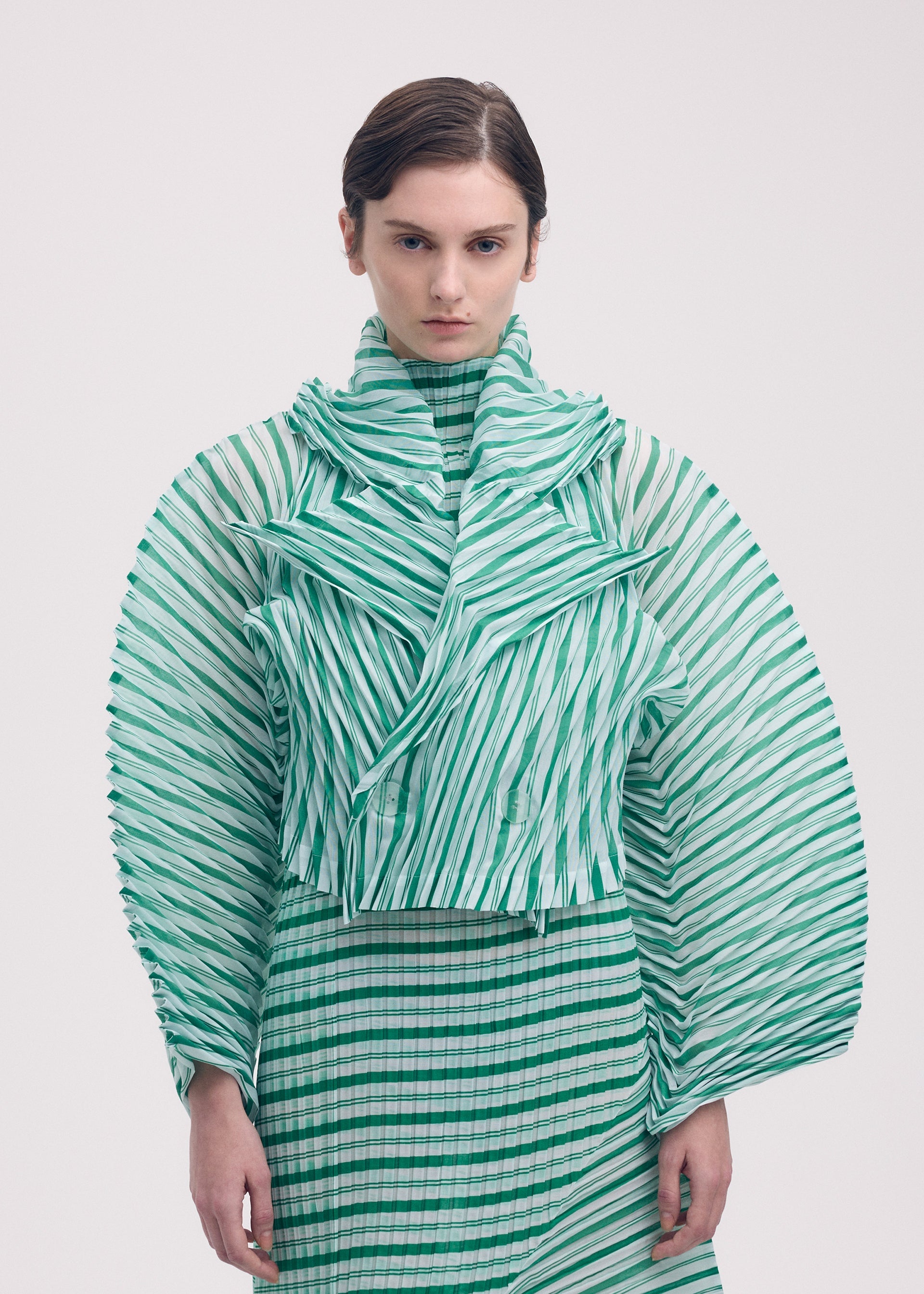 A model wears the Issey Miyake GENERIC STRIPES HAND PLEATS jacket.
