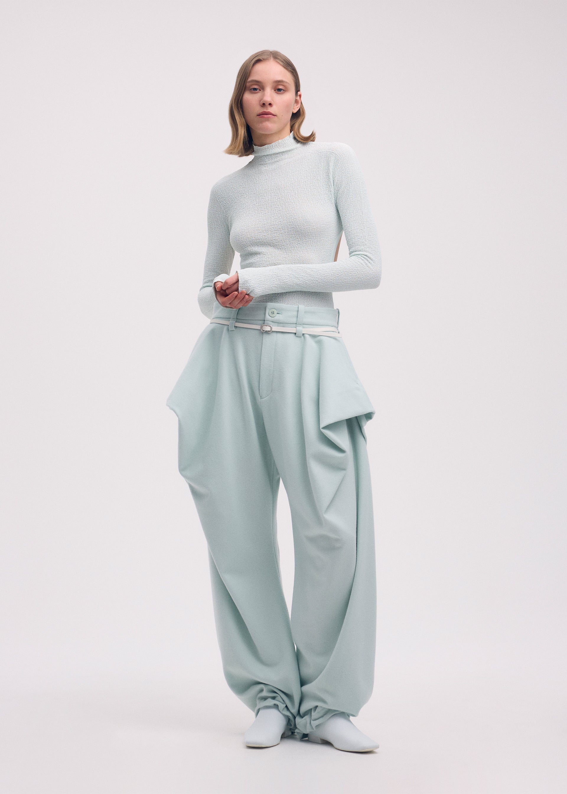 A model wears the Issey Miyake WOOL TWEED PANTS trousers.