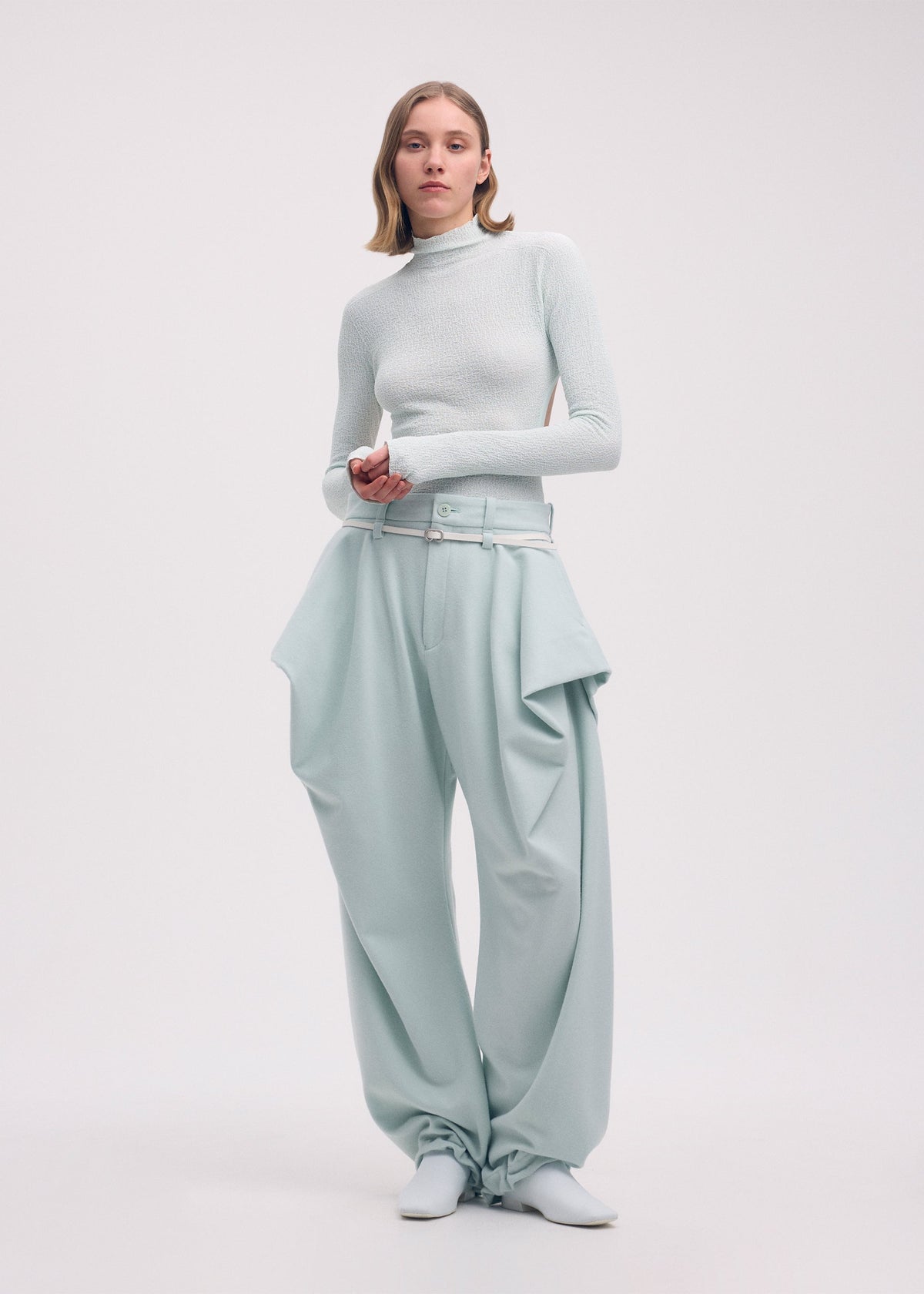 A model wears the Issey Miyake WOOL TWEED PANTS trousers.