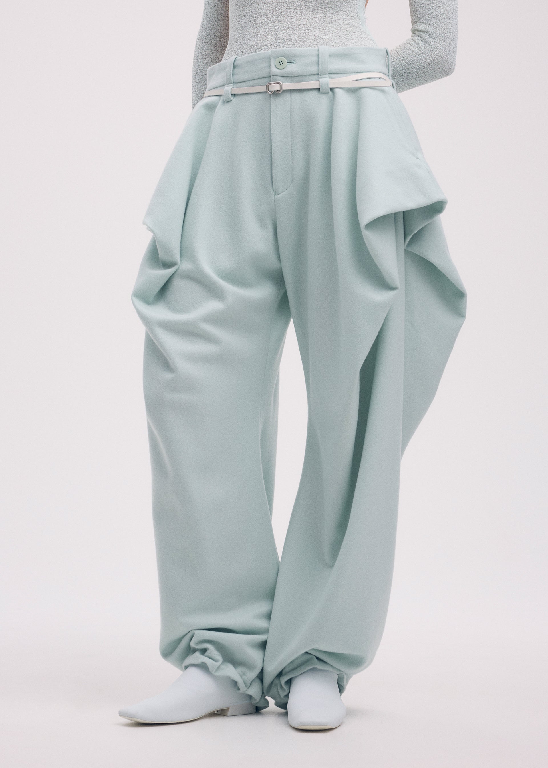 A model wears the Issey Miyake WOOL TWEED PANTS trousers.