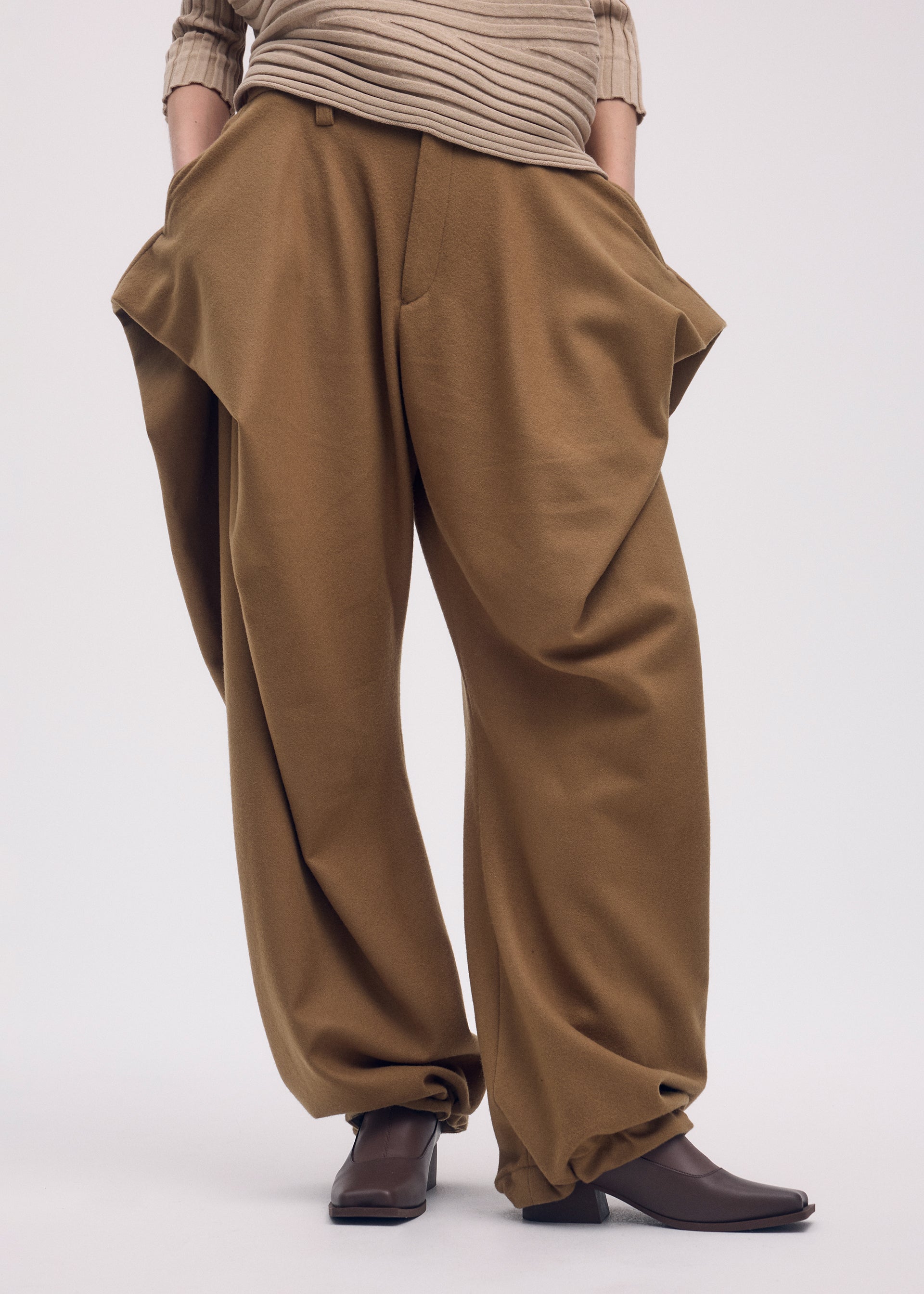 A model wears the Issey Miyake WOOL TWEED PANTS trousers.